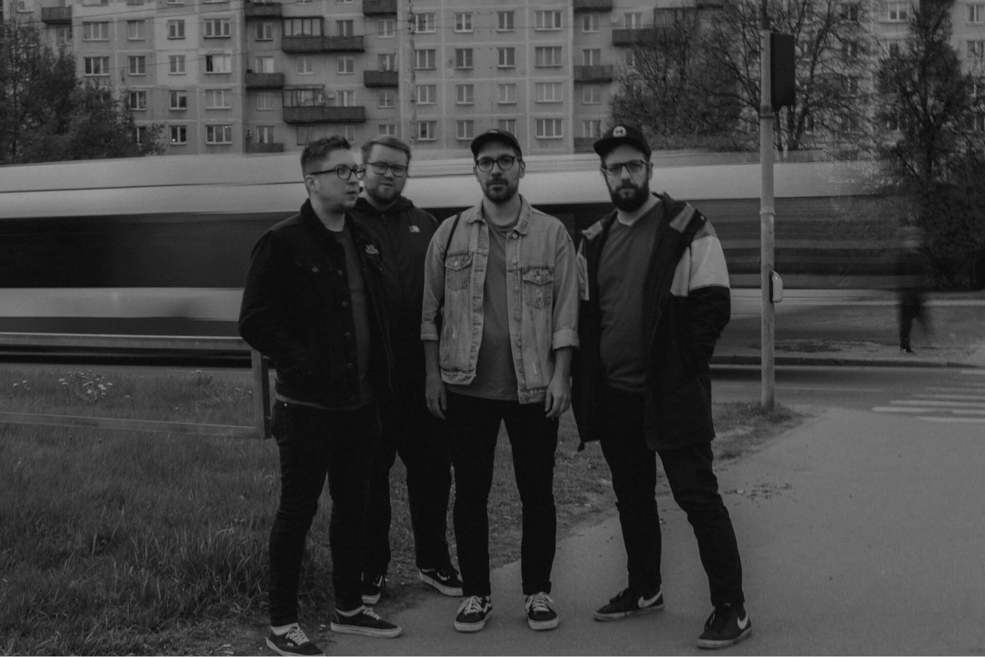 Have No Heroes punk rock band members standing, a blurry trolleybus is passing in the background